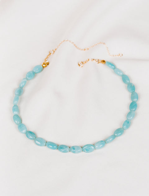 un collier en perles de Amazonite sur une feuille blanche