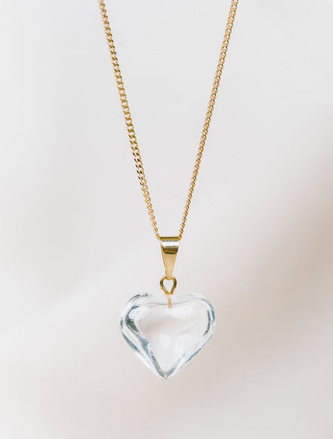 un collier avec un cristal en forme de cœur sur une chaîne dorée