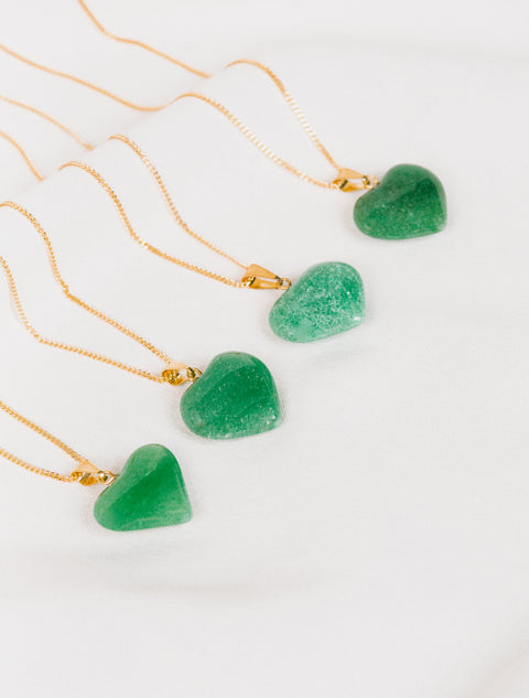 un groupe de trois pierres en forme de cœur vert sur une chaîne en or