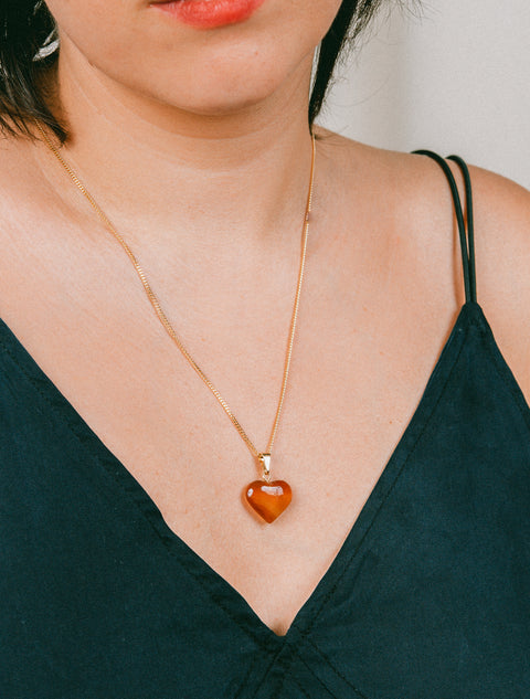 une femme porte un collier avec un pendentif en forme de cœur