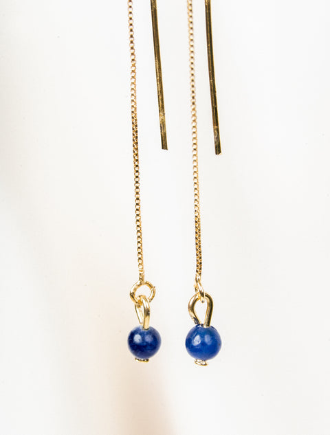 une paire de perles bleues suspendues à une chaîne en or