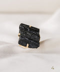 une bague en pierre noire posée sur une feuille blanche