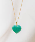 un pendentif en forme de cœur vert pend d'une chaîne en or
