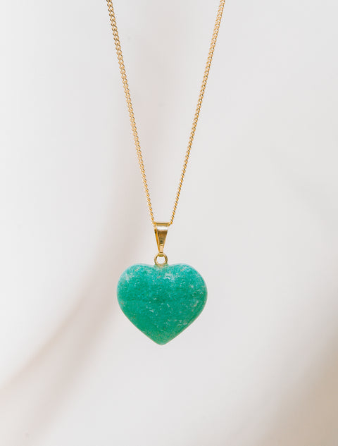 un pendentif en forme de cœur vert pend d'une chaîne en or