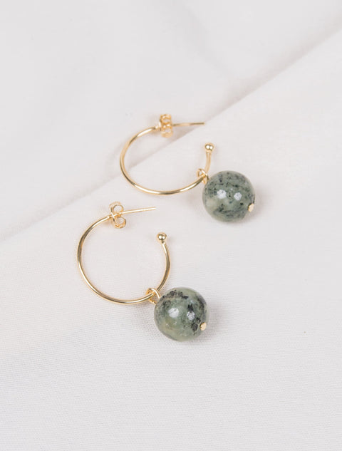 une paire de boucles d'oreilles en cercle doré avec des perles vertes