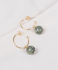 une paire de boucles d'oreilles en anneaux dorés avec des perles vertes