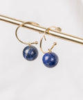 une paire de boucles d'oreilles en pierre bleue accrochée à une barre d'or