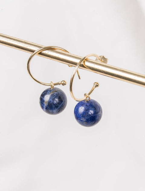 une paire de boucles d'oreilles en pierre bleue accrochée à une barre d'or