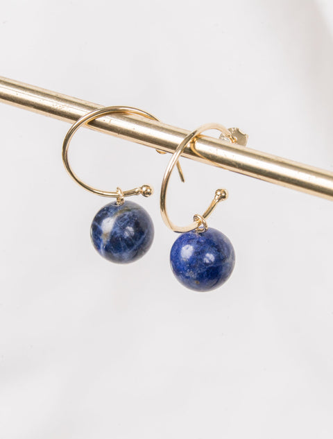 une paire de boucles d'oreilles en pierre bleue suspendue à une barre en or