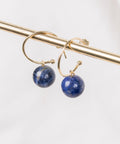 une paire de boucles d'oreilles en pierre bleue suspendues à une barre en or