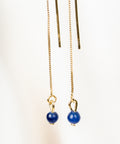 une paire de perles bleues suspendues à une chaîne en or