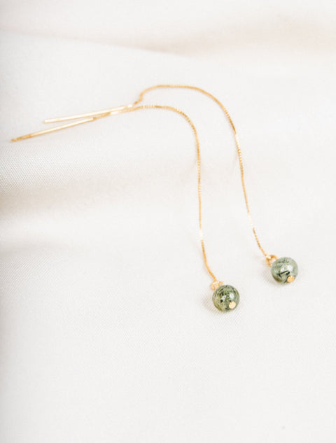 une paire de perles vertes suspendues à une chaîne en or
