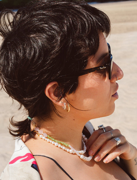 une femme portant des lunettes de soleil et un collier sur la plage