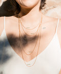 une femme portant un débardeur blanc et un collier en or